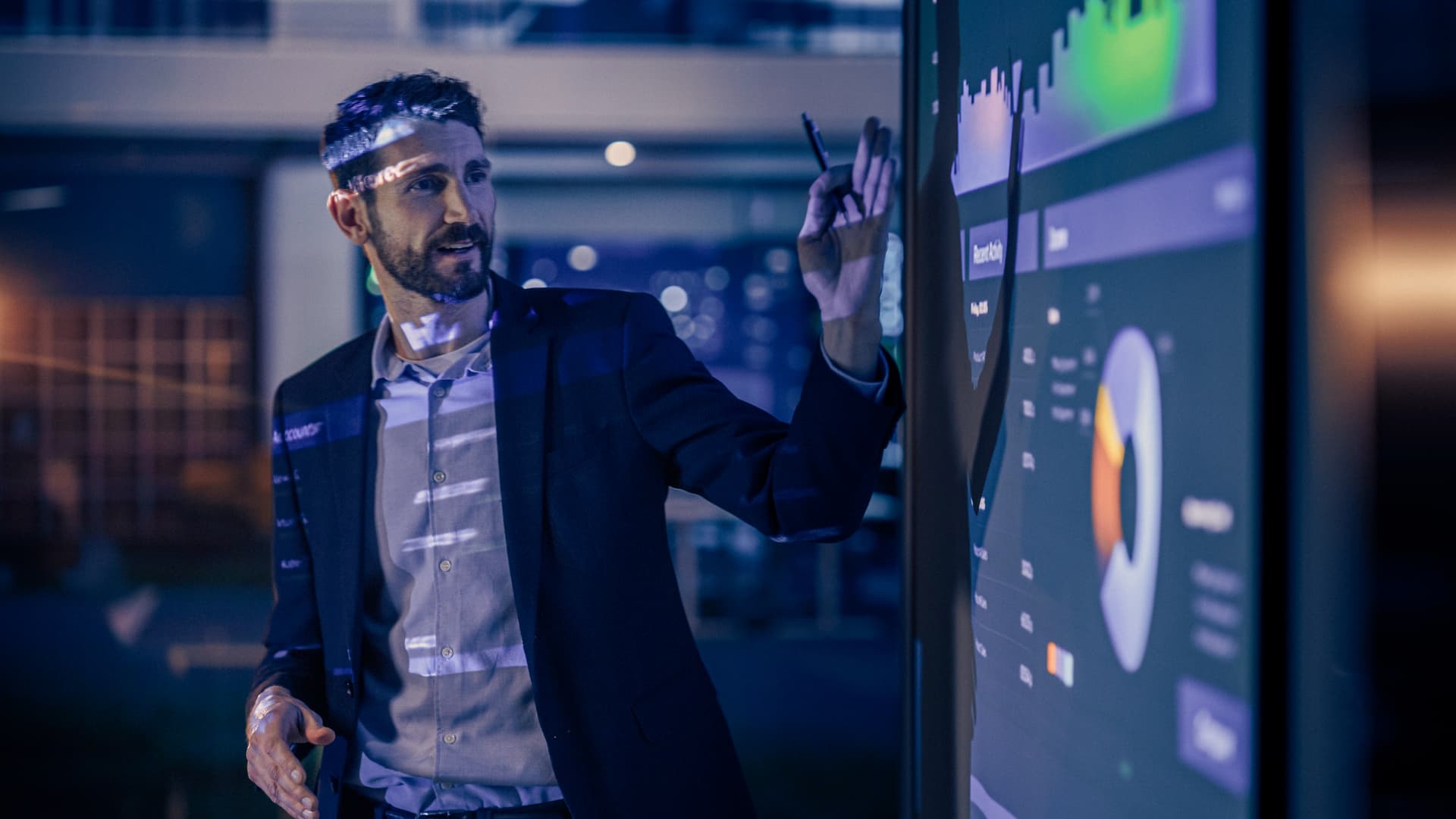 Conference Business Meeting Presentation: CEO Businessman Shows Data to Group of Investors, Businessspeople. Projector Screen Shows Graphs, Product Sales, Revenue Growth Strategy, e-Commerce Analysis