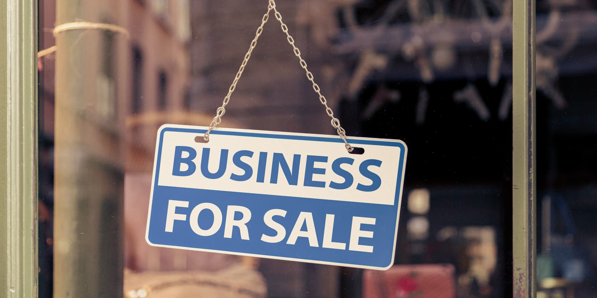Close-up on a white and blue sign in a window written inside it "Business for sale".